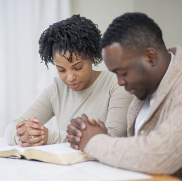 anniversary bible verses  man and woman with hands clasped praying together over bible